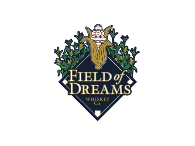 Logo with a corn cob featuring three baseballs at the top, surrounded by corn stalks. Below, a dark diamond shape displays the text Field of Dreams Whiskey Co. in gold and white lettering.